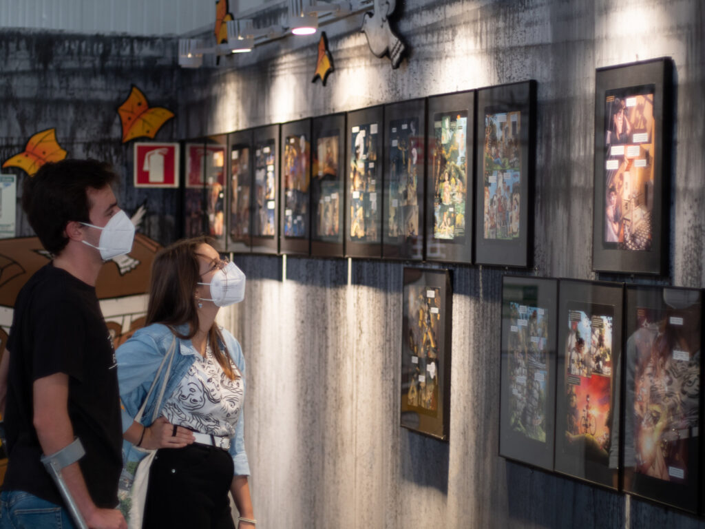 Dos visitantes observando una exposición de viñetas de cómic en una pared